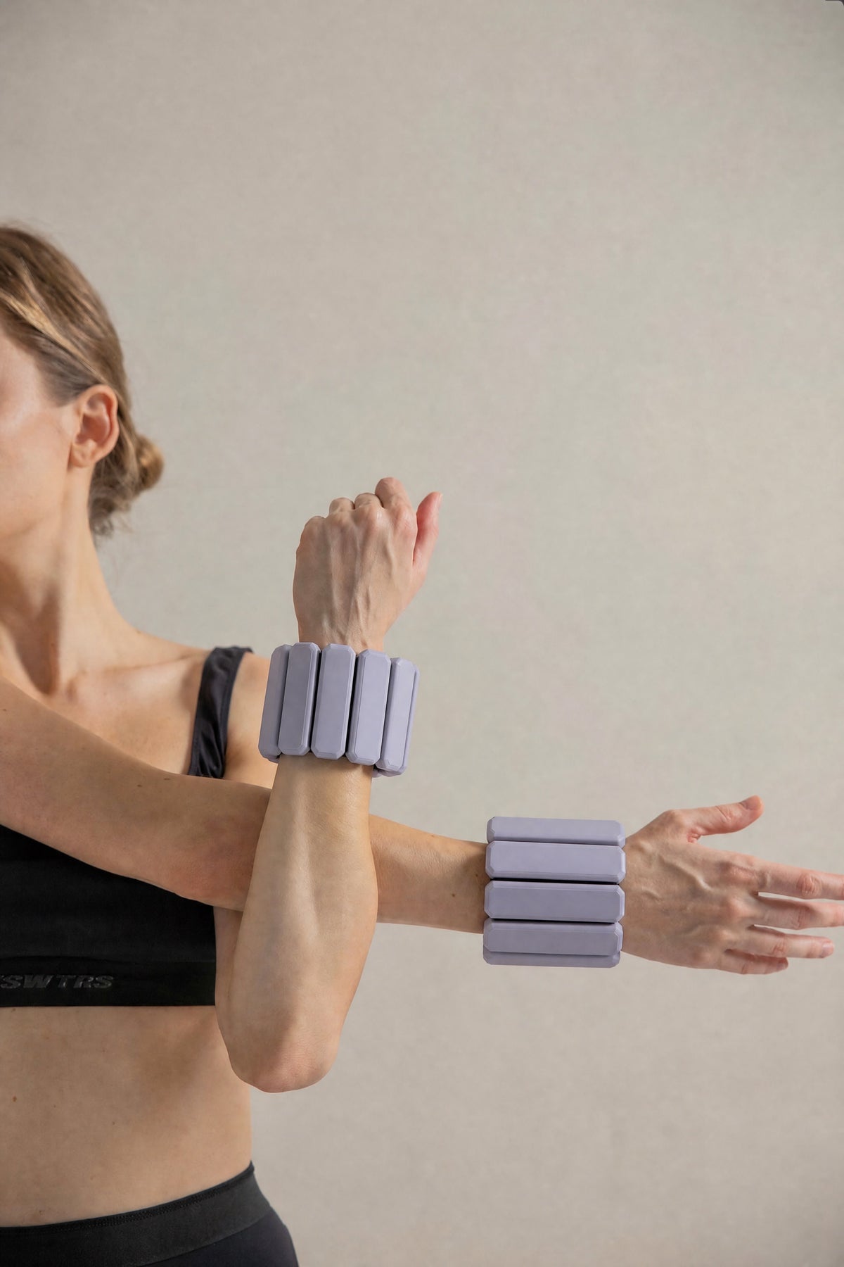 Обтяжувачі «Flex Form» 2x1 кг: лавандові обтяжувачі закріплені на обох зап'ястях під час тренування.